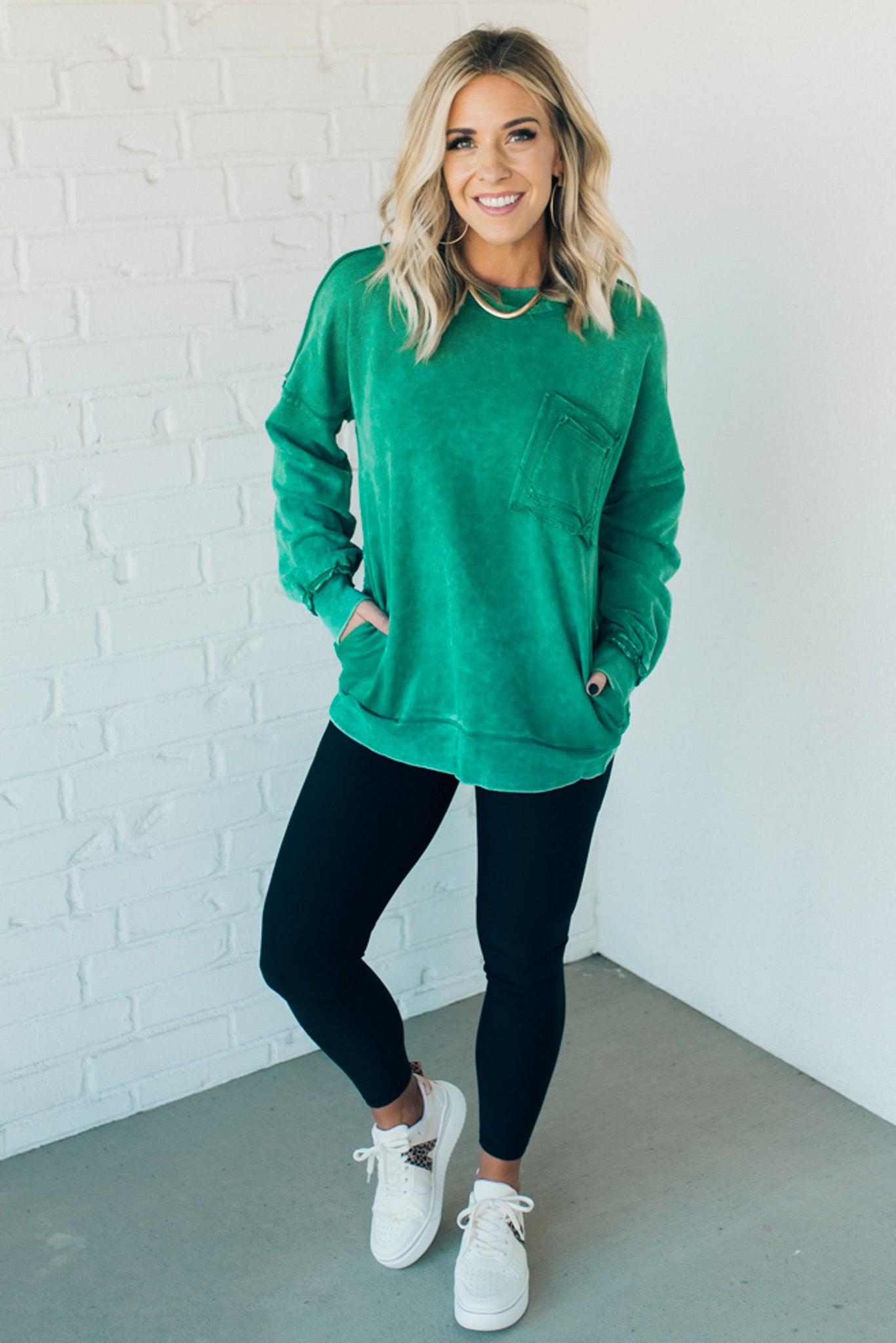 Blonde woman wearing a boyfriend fit drop shoulder sweatshirt pullover, with front pocket accent, exposed raw seams, and all over acid wash detail.