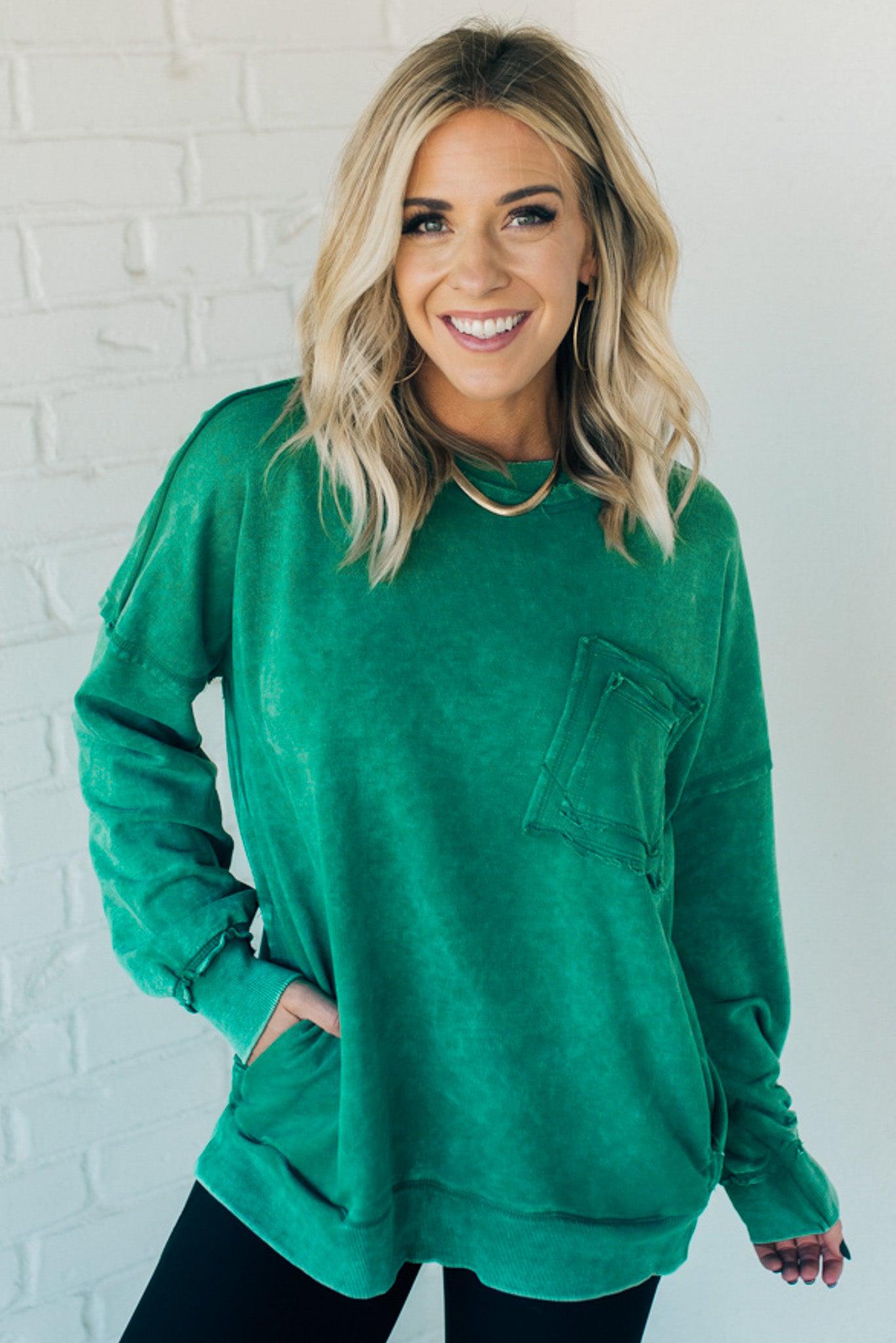 Blonde woman wearing a boyfriend fit drop shoulder sweatshirt pullover, with front pocket accent, exposed raw seams, and all over acid wash detail.