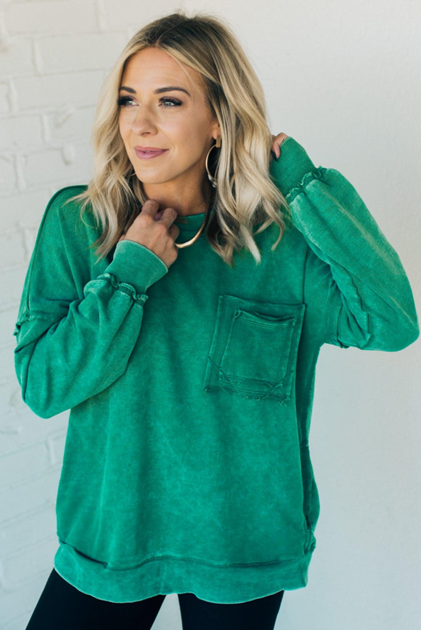 Blonde woman wearing a boyfriend fit drop shoulder sweatshirt pullover, with front pocket accent, exposed raw seams, and all over acid wash detail.
