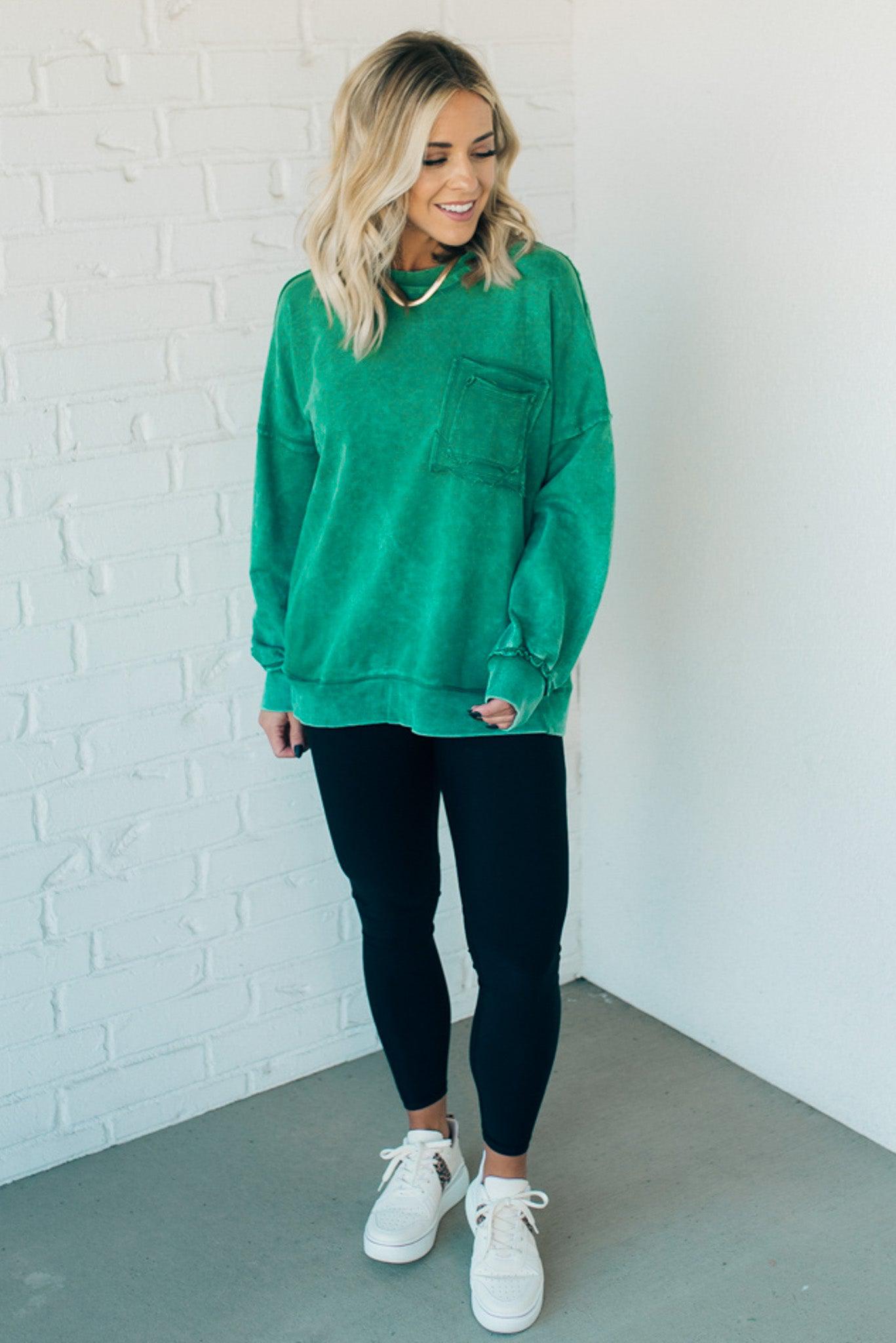 Blonde woman wearing a boyfriend fit drop shoulder sweatshirt pullover, with front pocket accent, exposed raw seams, and all over acid wash detail.