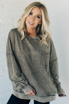 Blonde woman wearing a boyfriend fit drop shoulder sweatshirt pullover, with front pocket accent, exposed raw seams, and all over acid wash detail.