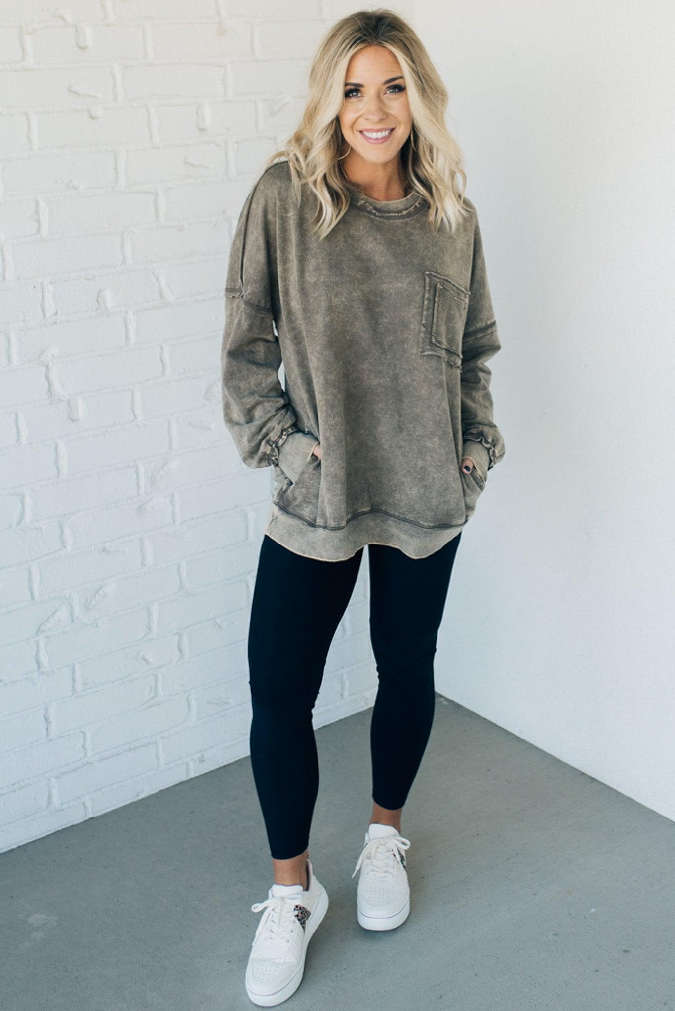 Blonde woman wearing a boyfriend fit drop shoulder sweatshirt pullover, with front pocket accent, exposed raw seams, and all over acid wash detail.
