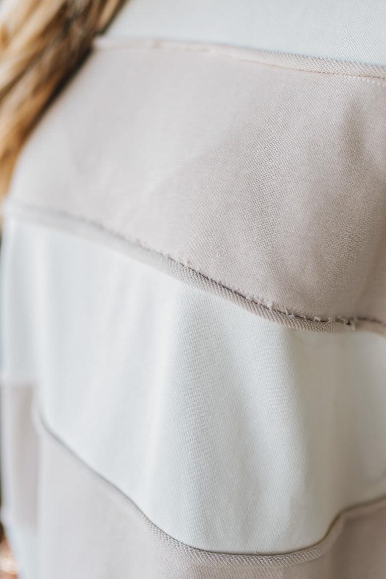 Close-up of a beige fabric with a subtle pattern, possibly from a garment.