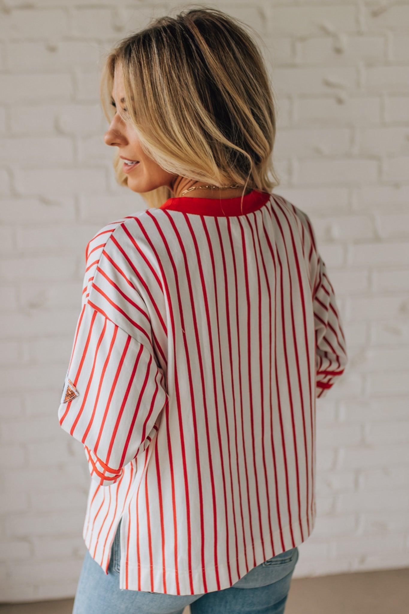 Woman wearing a red and white striped shirt against a white brick wall.