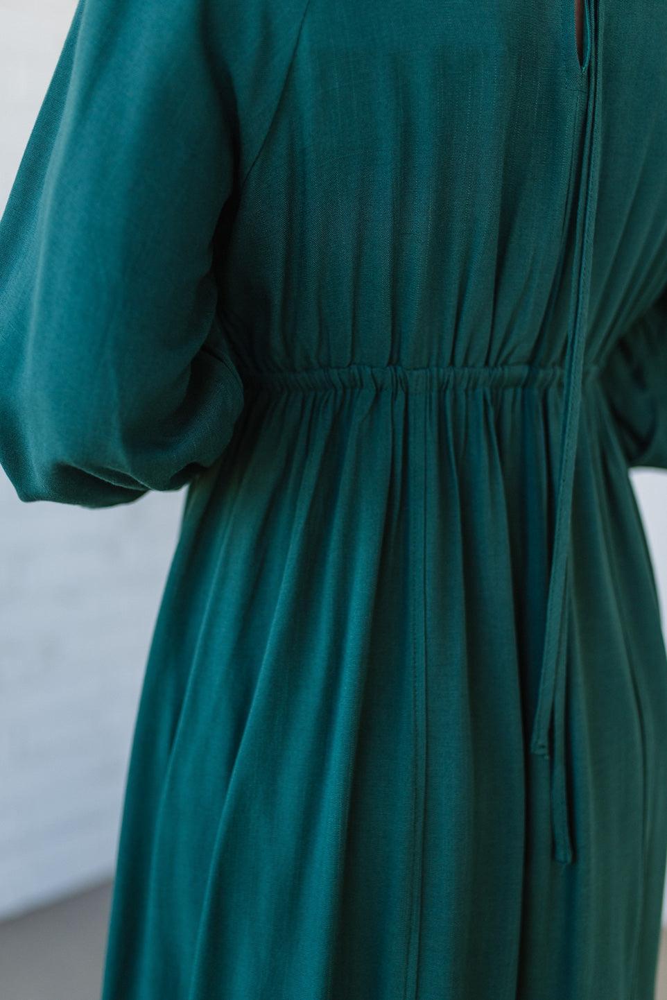 Blonde Woman Wearing a Gathered Long Sleeve Maxi Dress in the color Deep Forest.