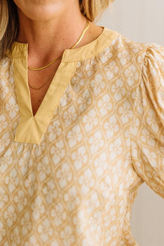 Close-up of a person wearing a patterned blouse with a neutral background
