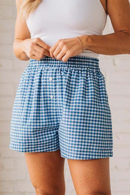 BLONDE WOMAN WEARING GINGHAM CHECK WOVEN BOXER SHORTS WITH SIDE POCKETS.