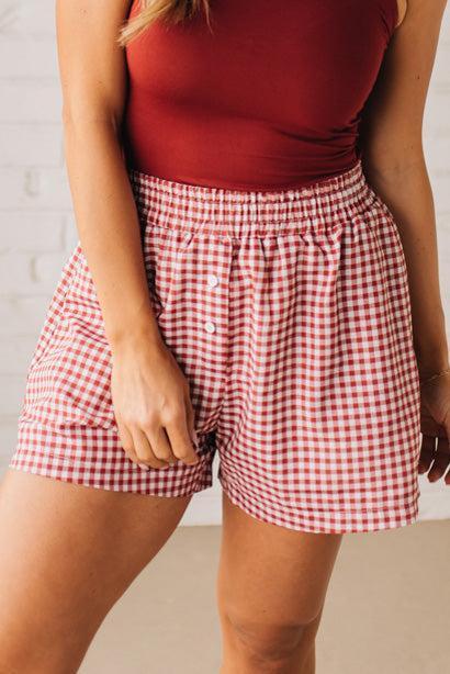 BLONDE WOMAN WEARING GINGHAM CHECK WOVEN BOXER SHORTS WITH SIDE POCKETS.