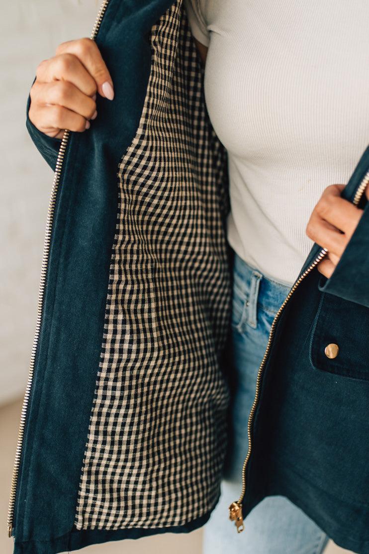 Person wearing a dark blue jacket with a checkered lining, white shirt, and light blue jeans.