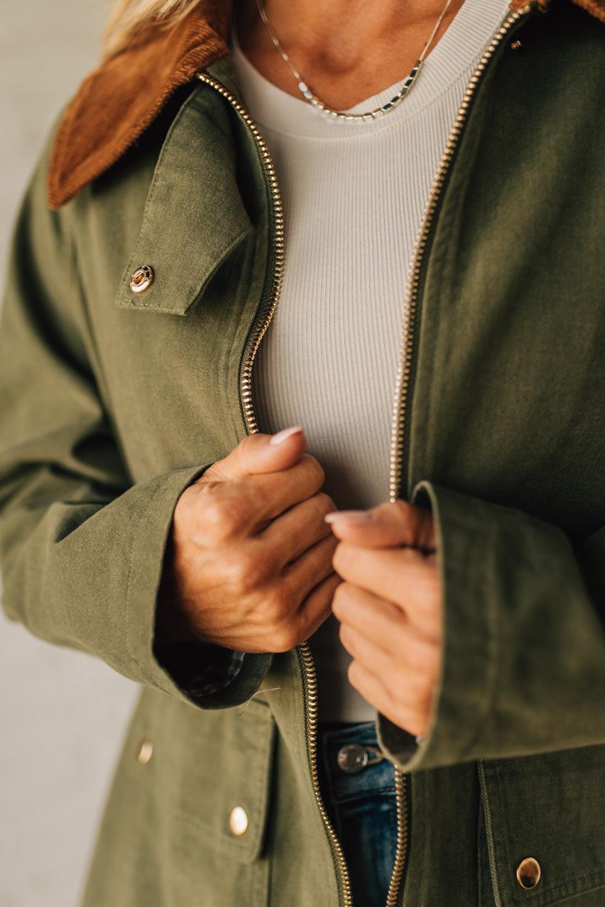 Person wearing a green jacket with a close-up of the zipper and collar.