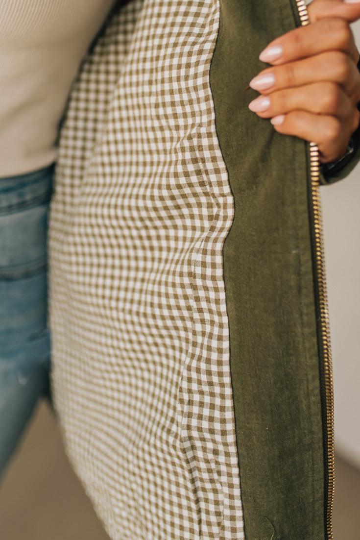Close-up of a person wearing a jacket with a gingham pattern and green zipper.