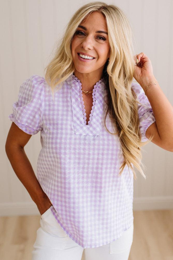 Woman wearing a purple checkered blouse with a plain background