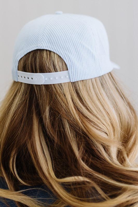 Person wearing a light blue cap with long, wavy hair.