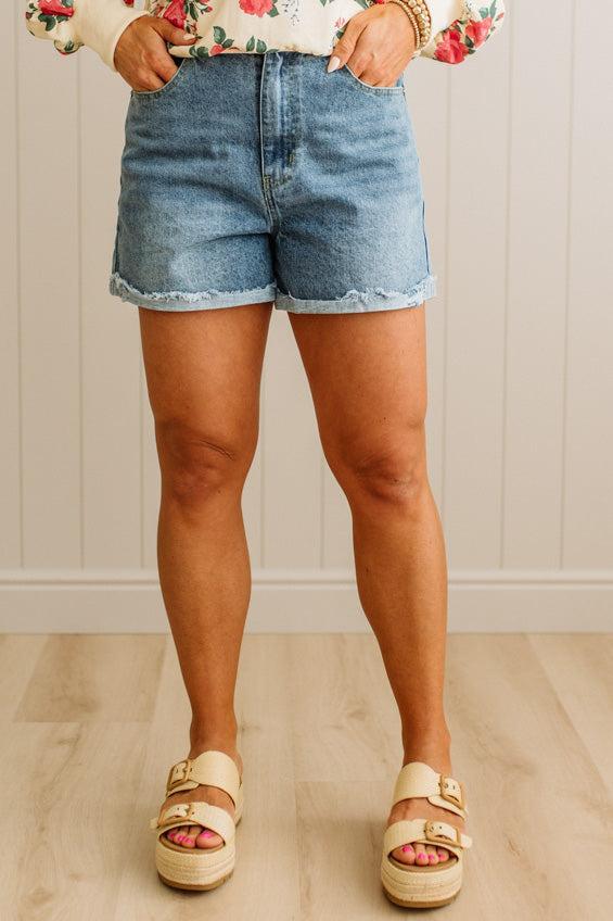 Person wearing denim shorts and sandals on a neutral background