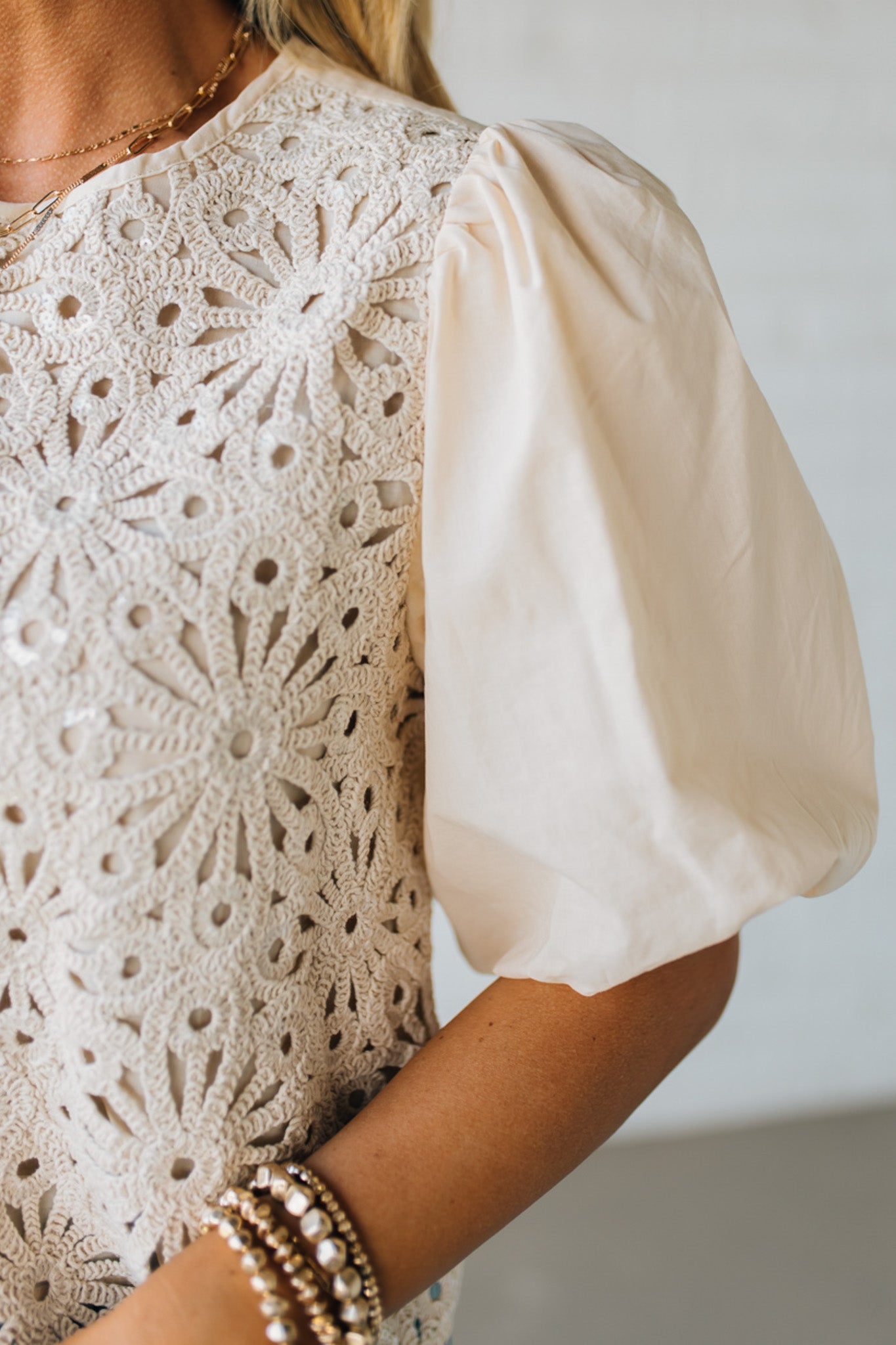 Blonde woman wearing a Mix Media Sequin Crochet Bodice Woven Blouse in cream.