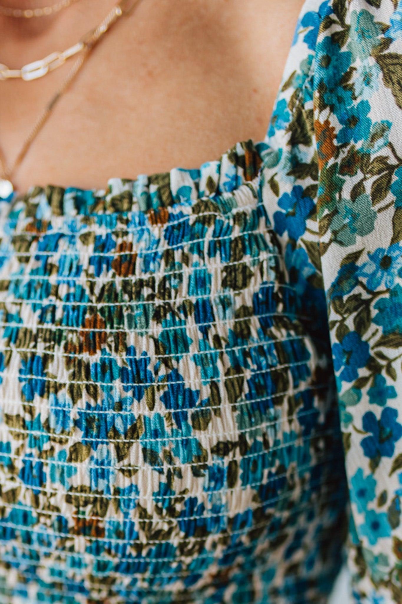 Blonde Woman Wearing A Floral Print Smocked Bodice Tiered Midi Dress.