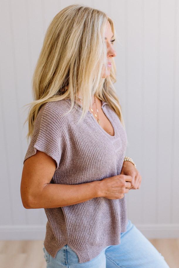 Blonde woman wearing a short sleeve v-neck ribbed texture sweater with center patch accent in mocha.