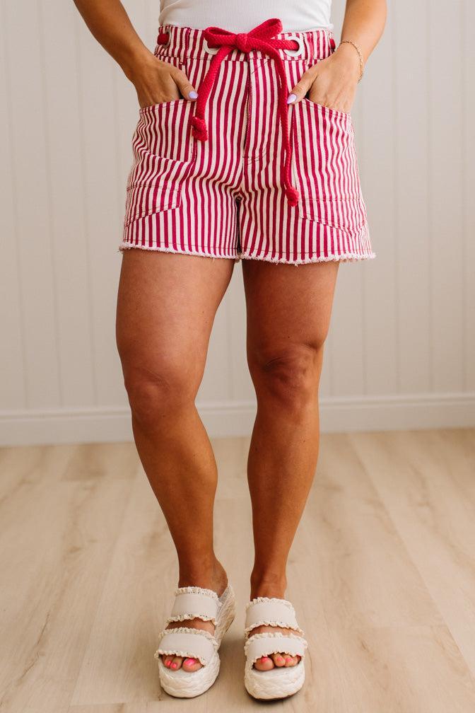 Woman wearing red and white striped shorts with red braided belt through grommets on waist.