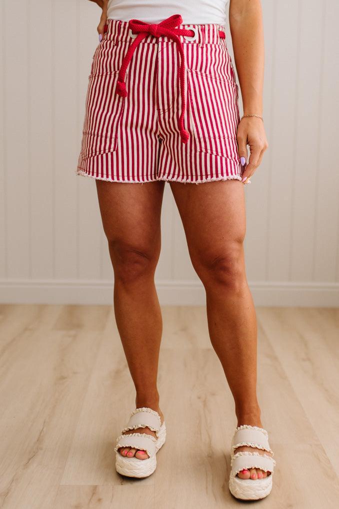 Woman wearing red and white striped shorts with red braided belt through grommets on waist.