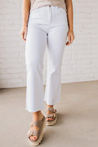 Woman wearing white cropped jeans with chunky tan sandals.
