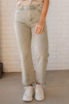 Blonde woman wearing light olive acid wash crop jeans with frayed ankle.