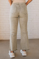 Blonde woman wearing light olive acid wash crop jeans with frayed ankle.