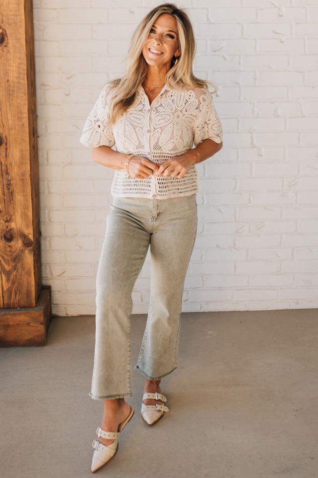 Blonde woman wearing light olive acid wash crop jeans with frayed ankle.