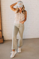 Blonde woman wearing light olive acid wash crop jeans with frayed ankle.