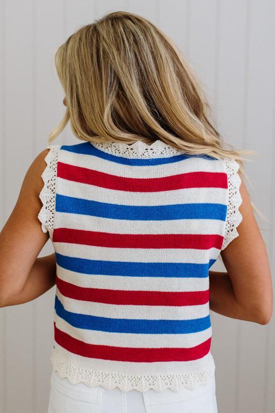 Person wearing a red, white, and blue striped sleeveless top with lace trim.