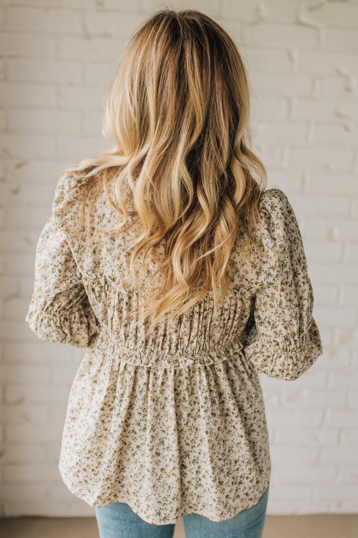 Woman wearing a floral blouse with a white brick wall background