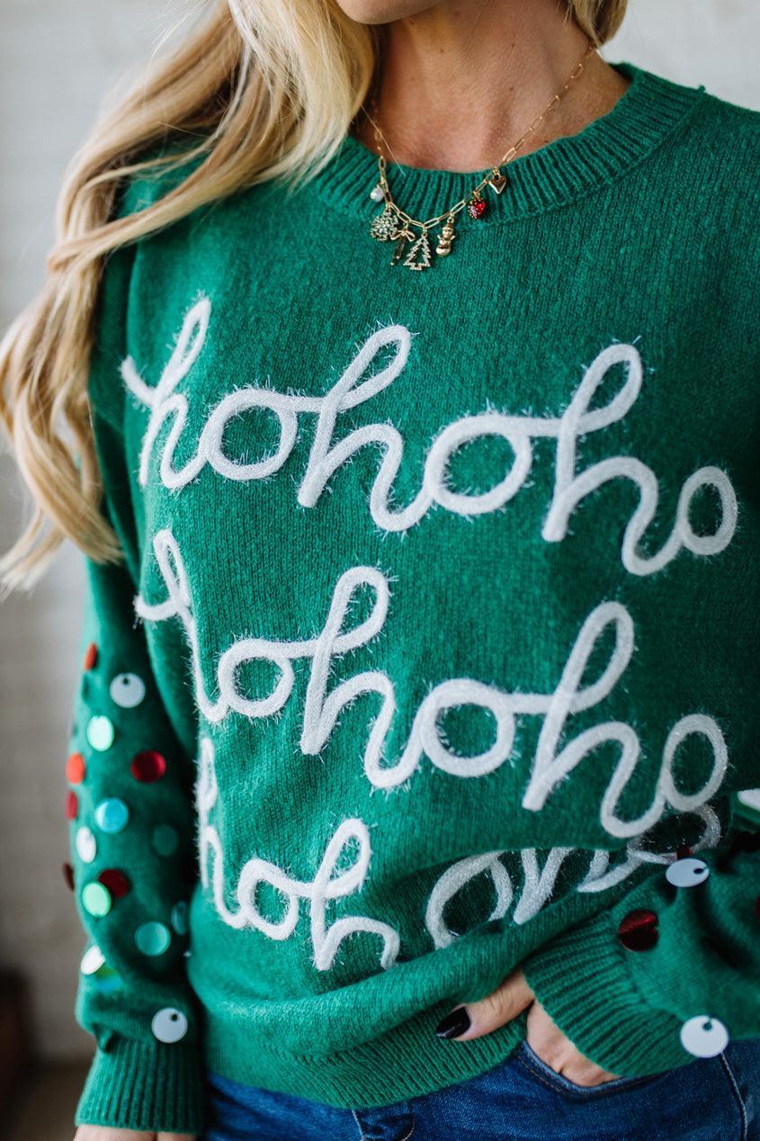 Green sweater with 'ho ho ho' text worn by a person.