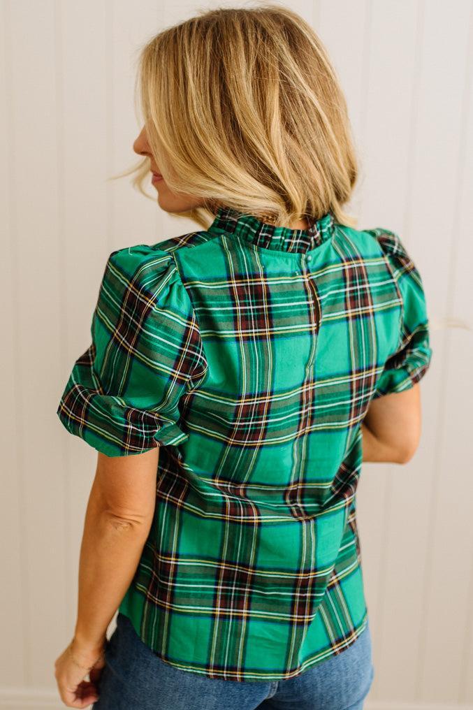 Woman wearing a green plaid shirt with puffed sleeves against a plain background