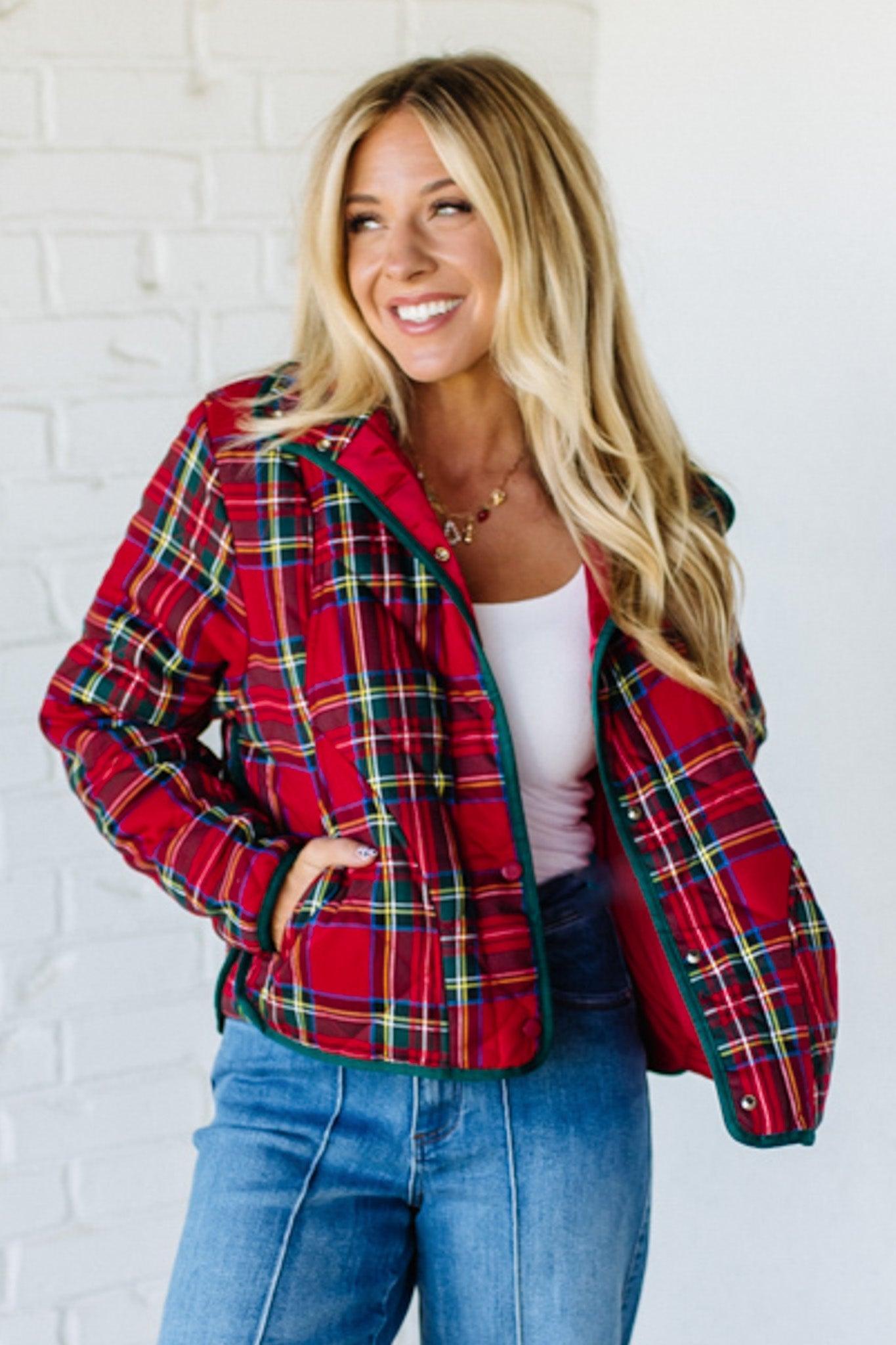 Woman wearing a red plaid jacket against a white brick wall