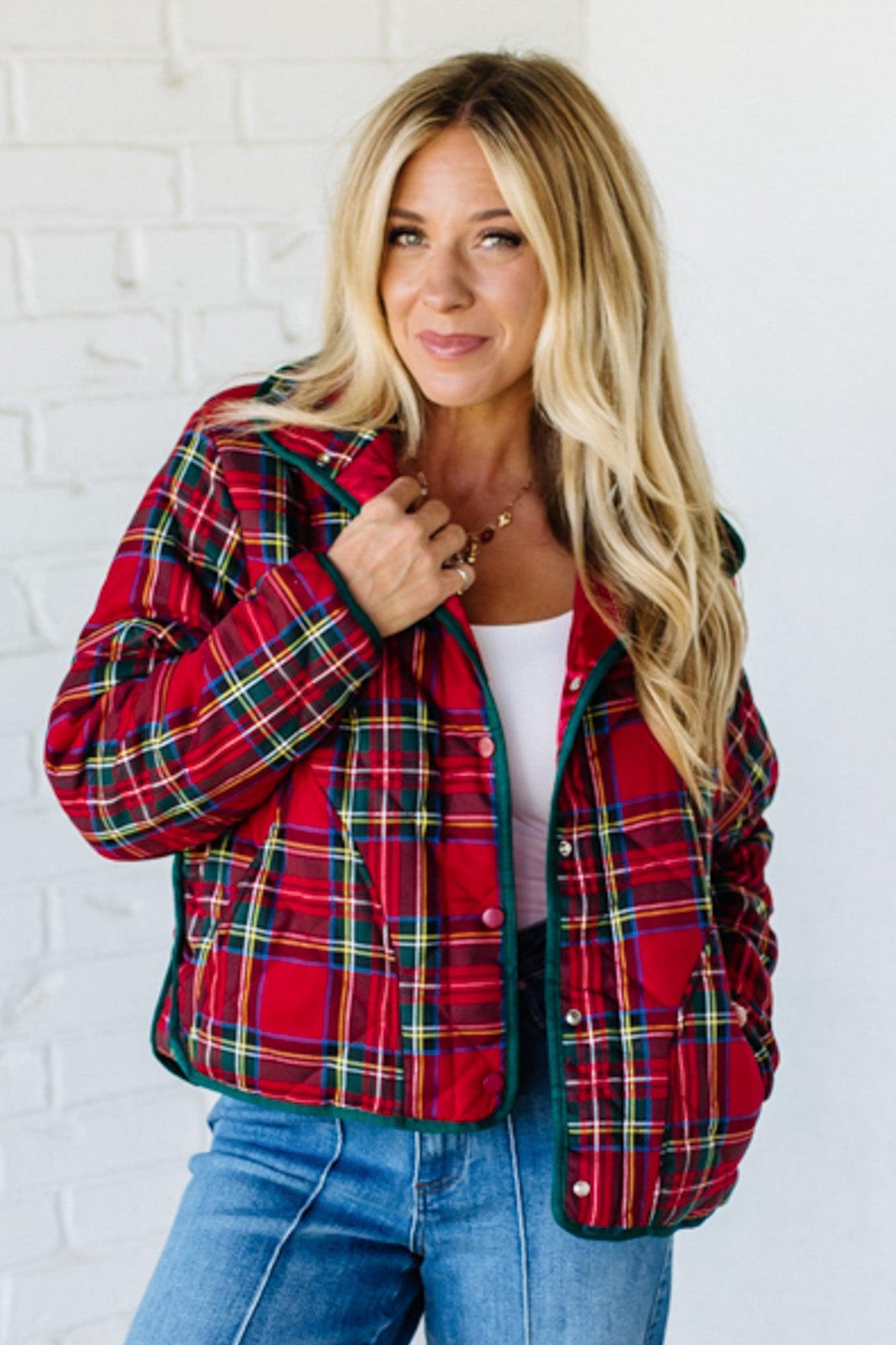 Woman wearing a red plaid jacket against a white brick wall