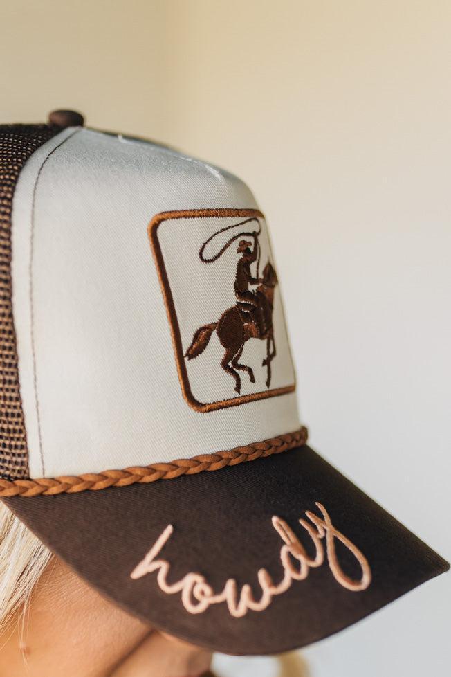 Trucker hat with embroidered design and text held by a person