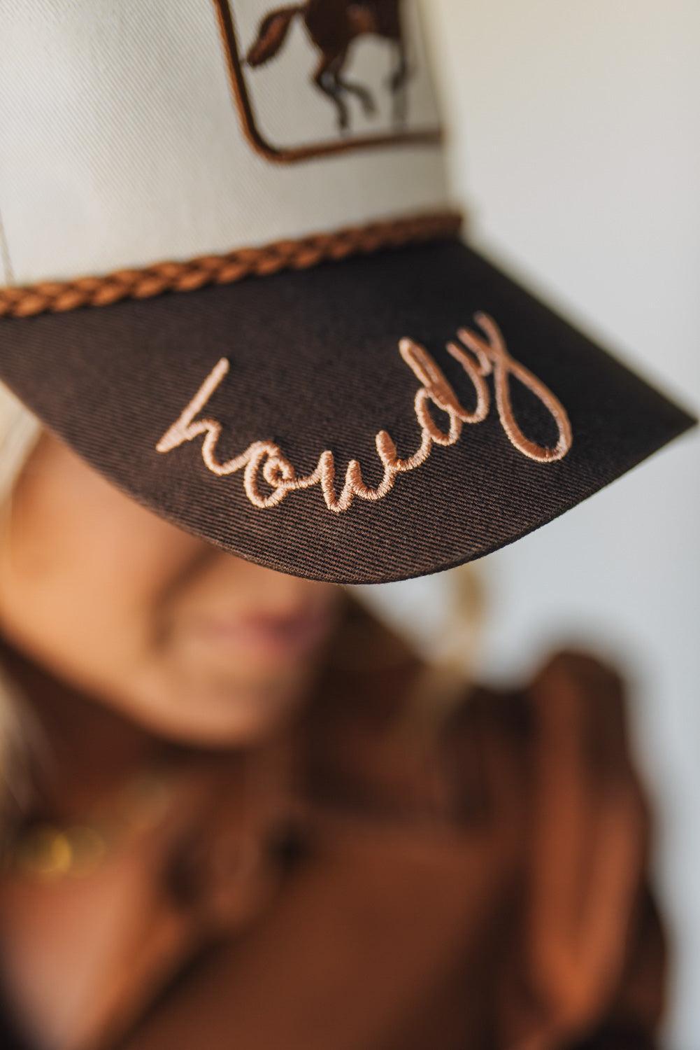 Trucker hat with embroidered design and text held by a person