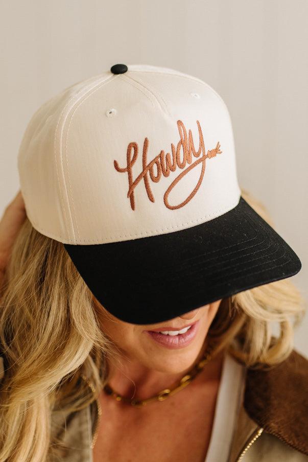 Person wearing a cap with 'Howdy' text on a neutral background