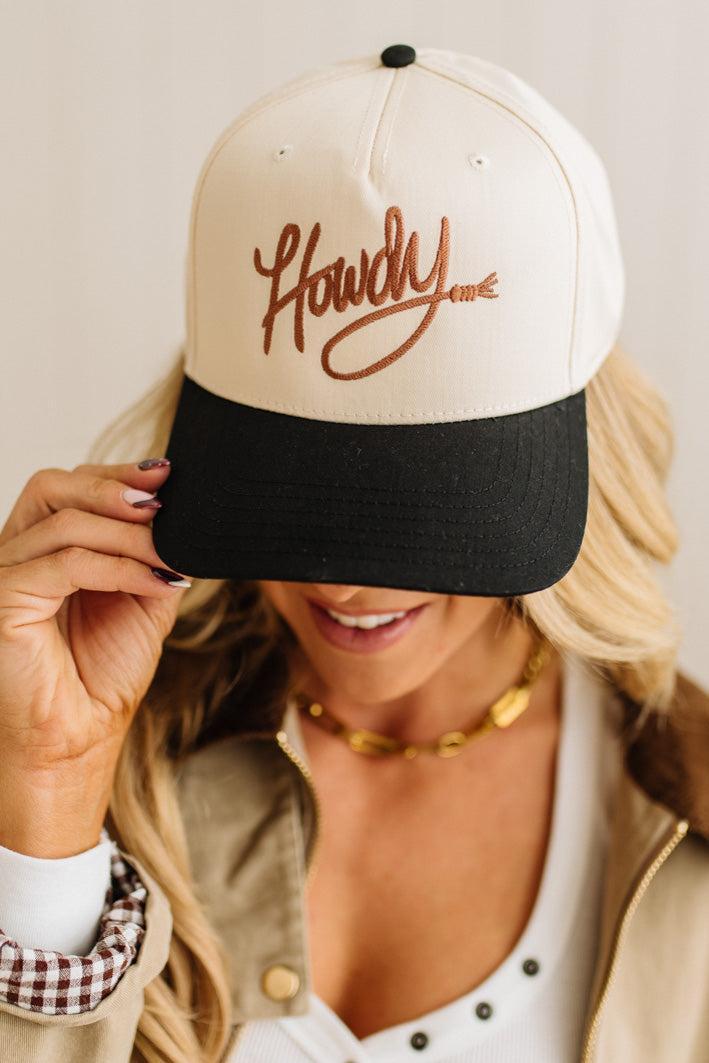 Person wearing a cap with 'Howdy' text on a plain background