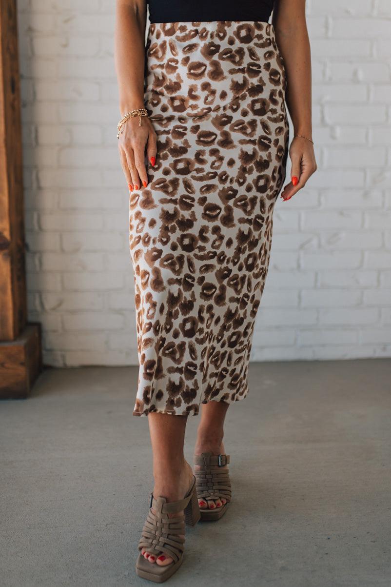 WOMAN WEARING AN ANIMAL PRINT BIAS CUT SATIN MIDI SKIRT.