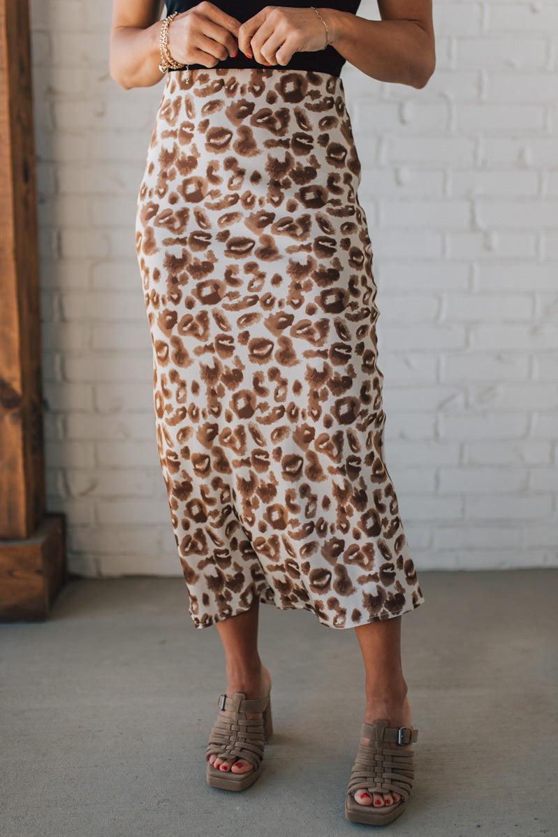 WOMAN WEARING AN ANIMAL PRINT BIAS CUT SATIN MIDI SKIRT.