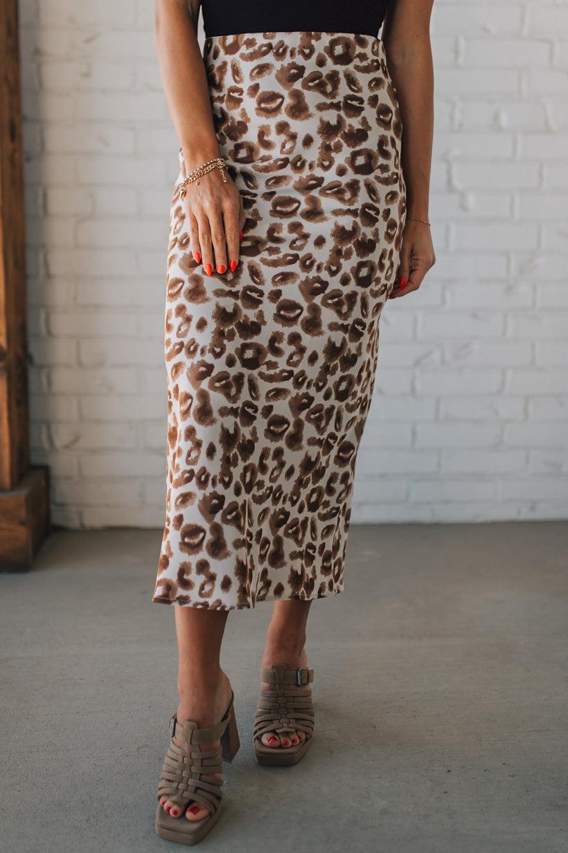 WOMAN WEARING AN ANIMAL PRINT BIAS CUT SATIN MIDI SKIRT.