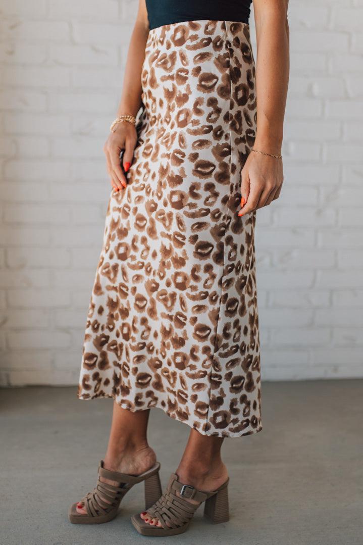 WOMAN WEARING AN ANIMAL PRINT BIAS CUT SATIN MIDI SKIRT.