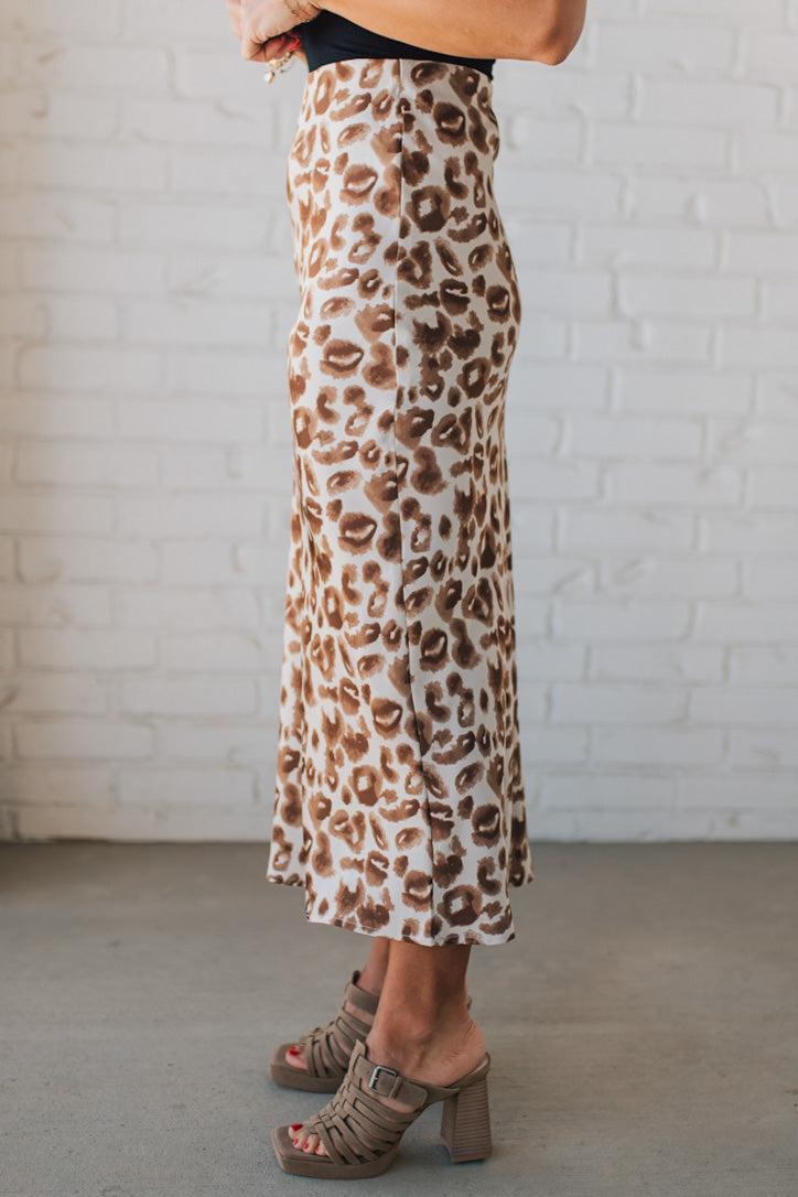 WOMAN WEARING AN ANIMAL PRINT BIAS CUT SATIN MIDI SKIRT.