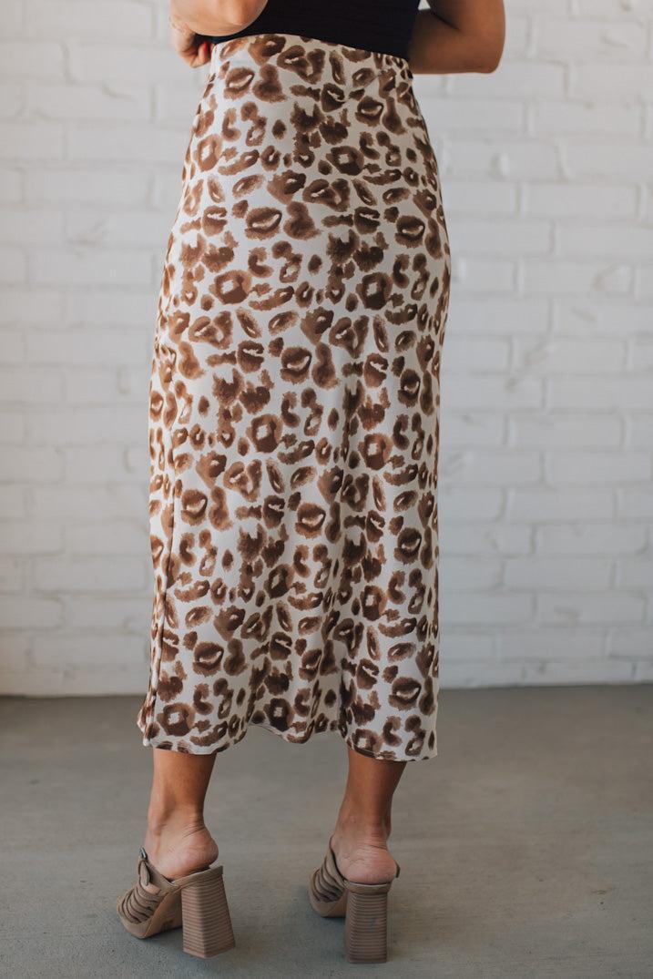 WOMAN WEARING AN ANIMAL PRINT BIAS CUT SATIN MIDI SKIRT.