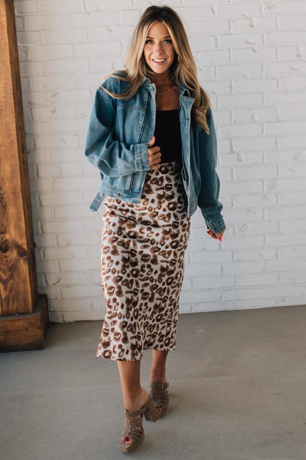 WOMAN WEARING AN ANIMAL PRINT BIAS CUT SATIN MIDI SKIRT.