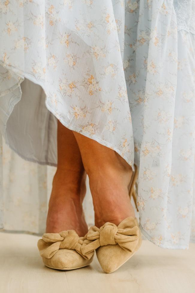 Beige shoes with large bows worn with a light floral dress.