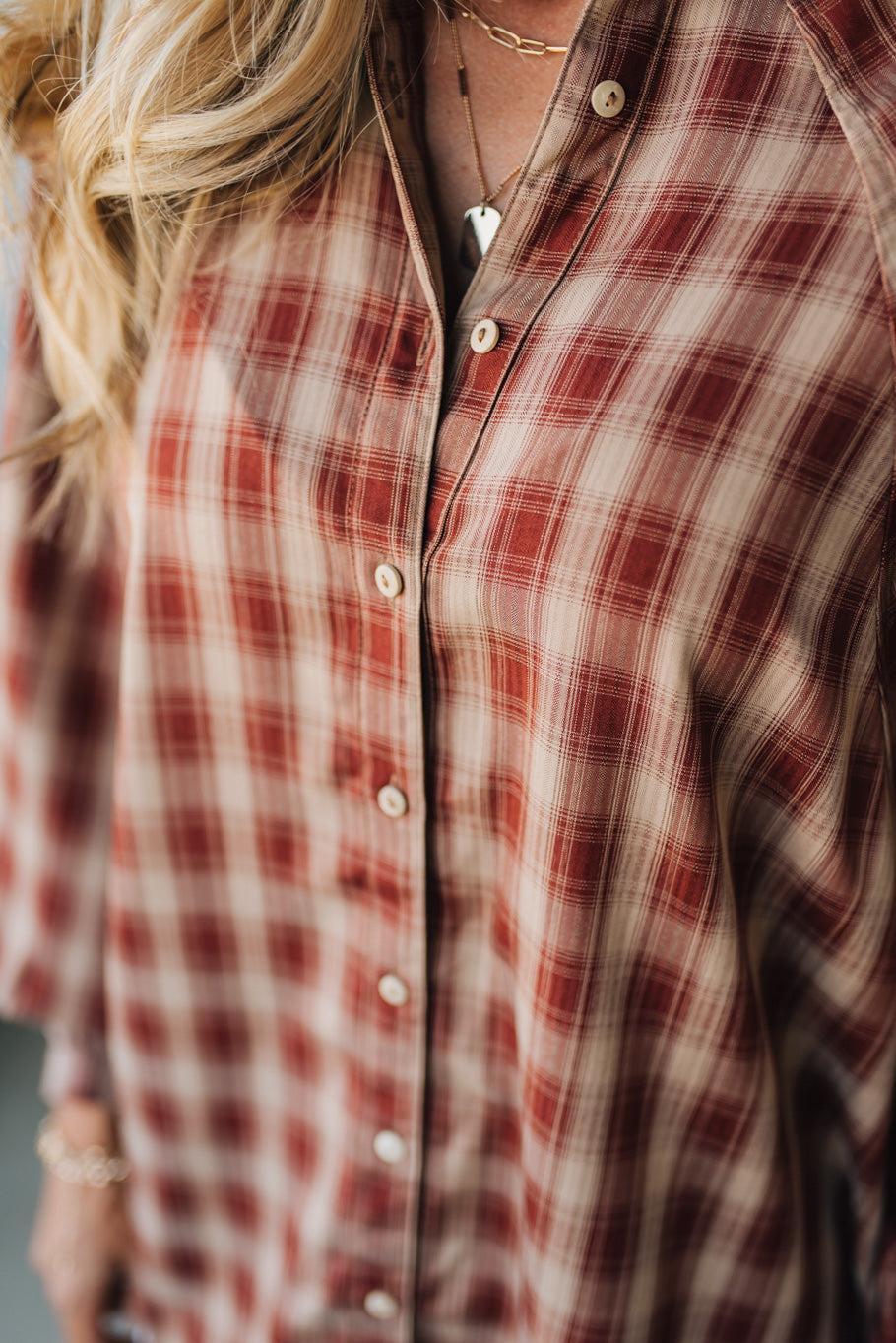 Close-up of a person wearing a red and brown plaid shirt.