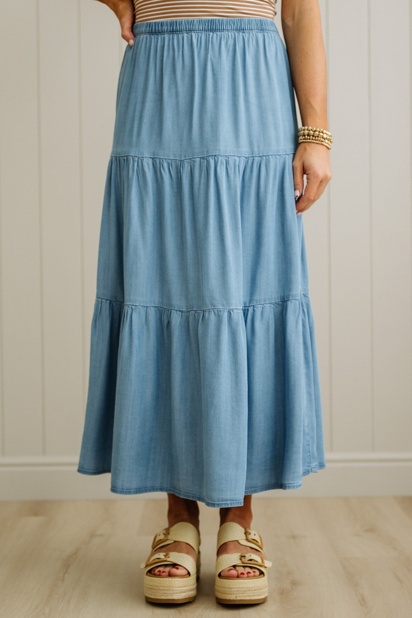 Person wearing a blue tiered skirt with a neutral background