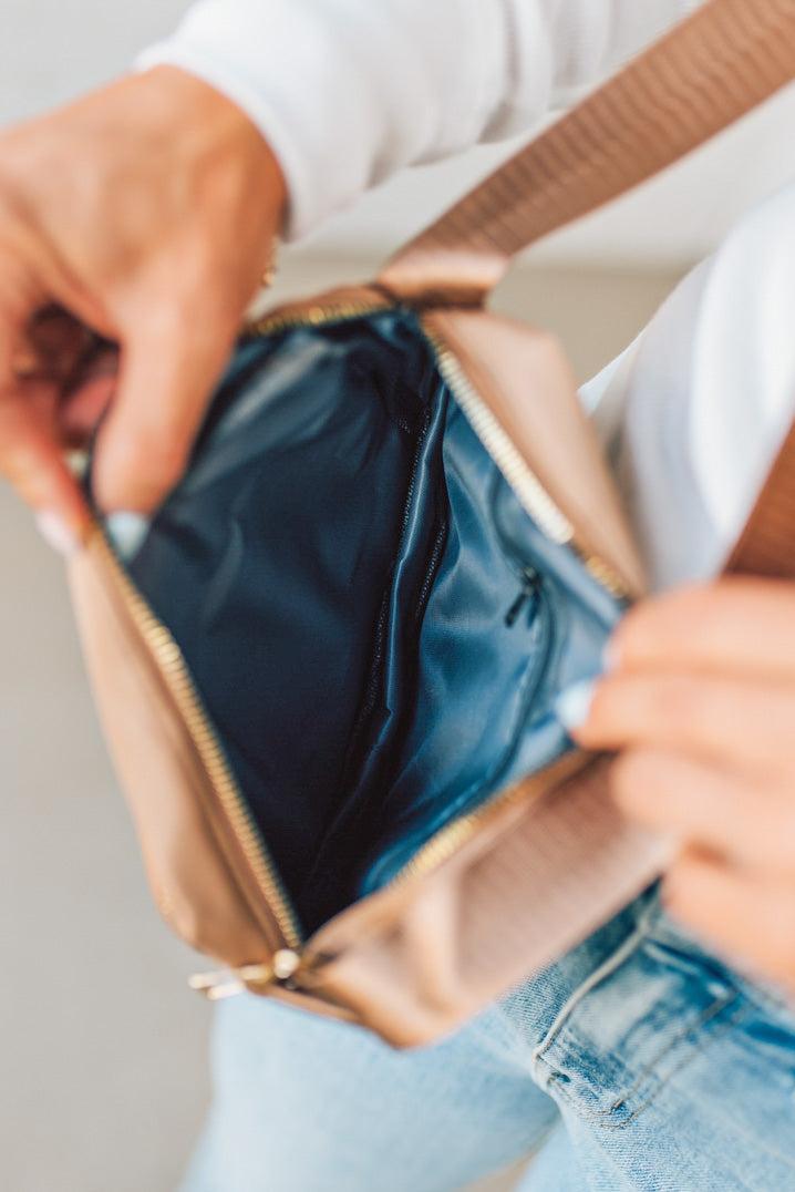 Person opening a gold handbag with a neutral background