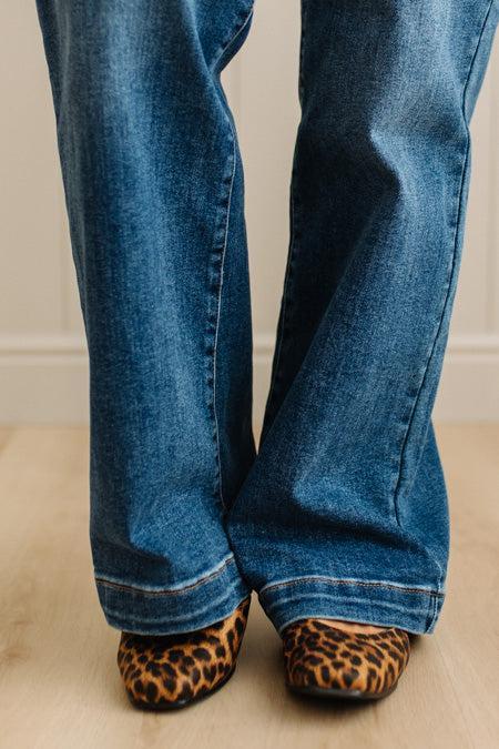 Leopard print flats with a gold buckle worn with rolled-up jeans on a neutral background